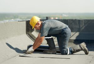 A roofing contractor places a roof patch on a flat roof.