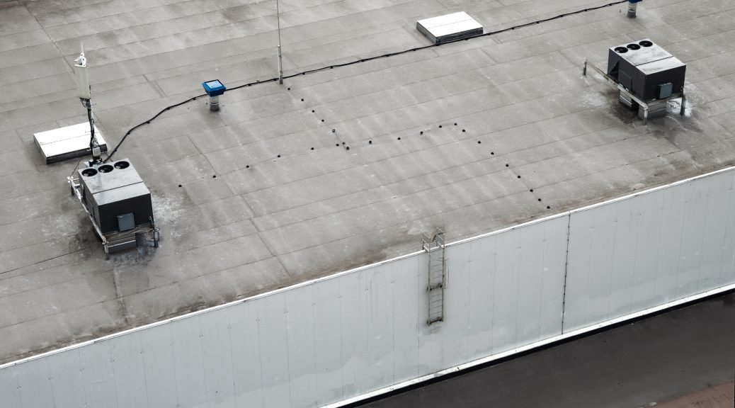 A commercial roof with wiring running across it, weaving through skylights and HVAC units.