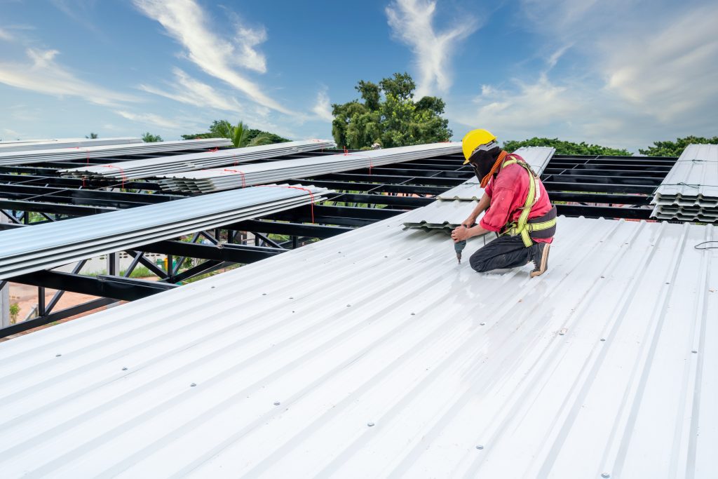 a roofing contractor works on a commercial building’s metal roof