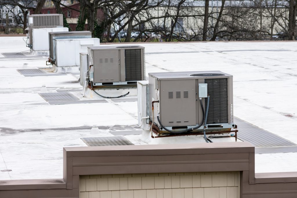A view of an industrial roofing system with multiple HVAC systems in a row.