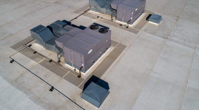 Two large HVAC units set onto a wide open commercial roof