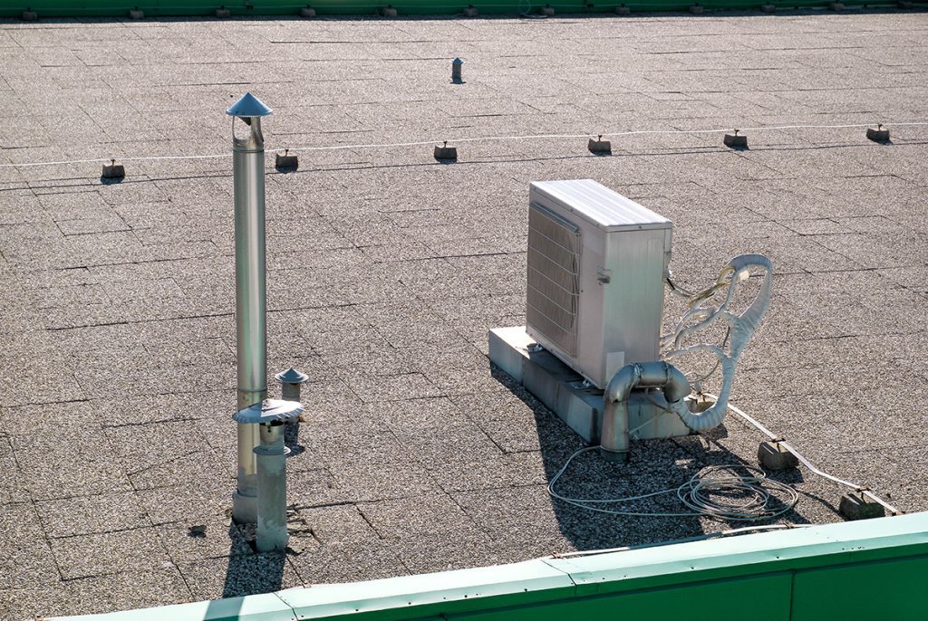 A close view of a low-slope tile roof with an AC unit on top