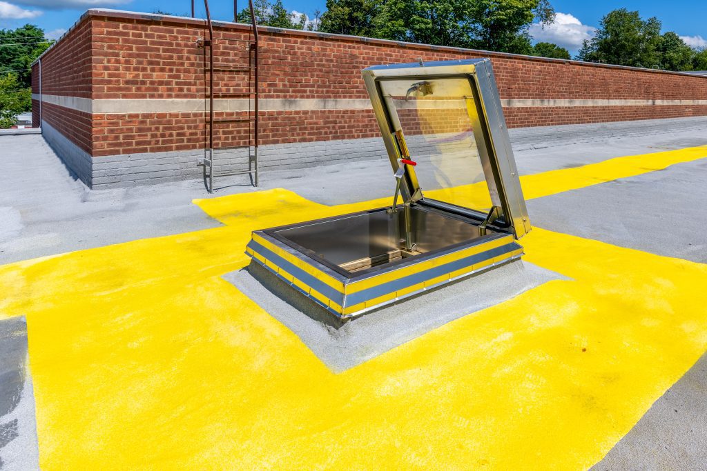 A flat roof with a skylight built into it with a bright yellow section painted around it
