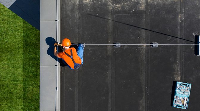 A view from above of a roofing contractor working on a flat, commercial roof.