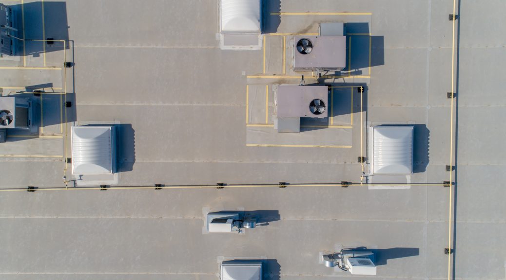 An overhead view of a PVC roof with multiple HVAC units and skylights placed on it.