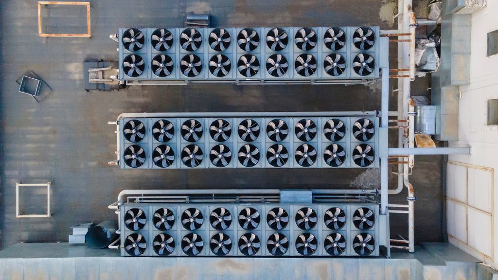 An overhead view of a grey commercial roof with two rows of large air-conditioning units.